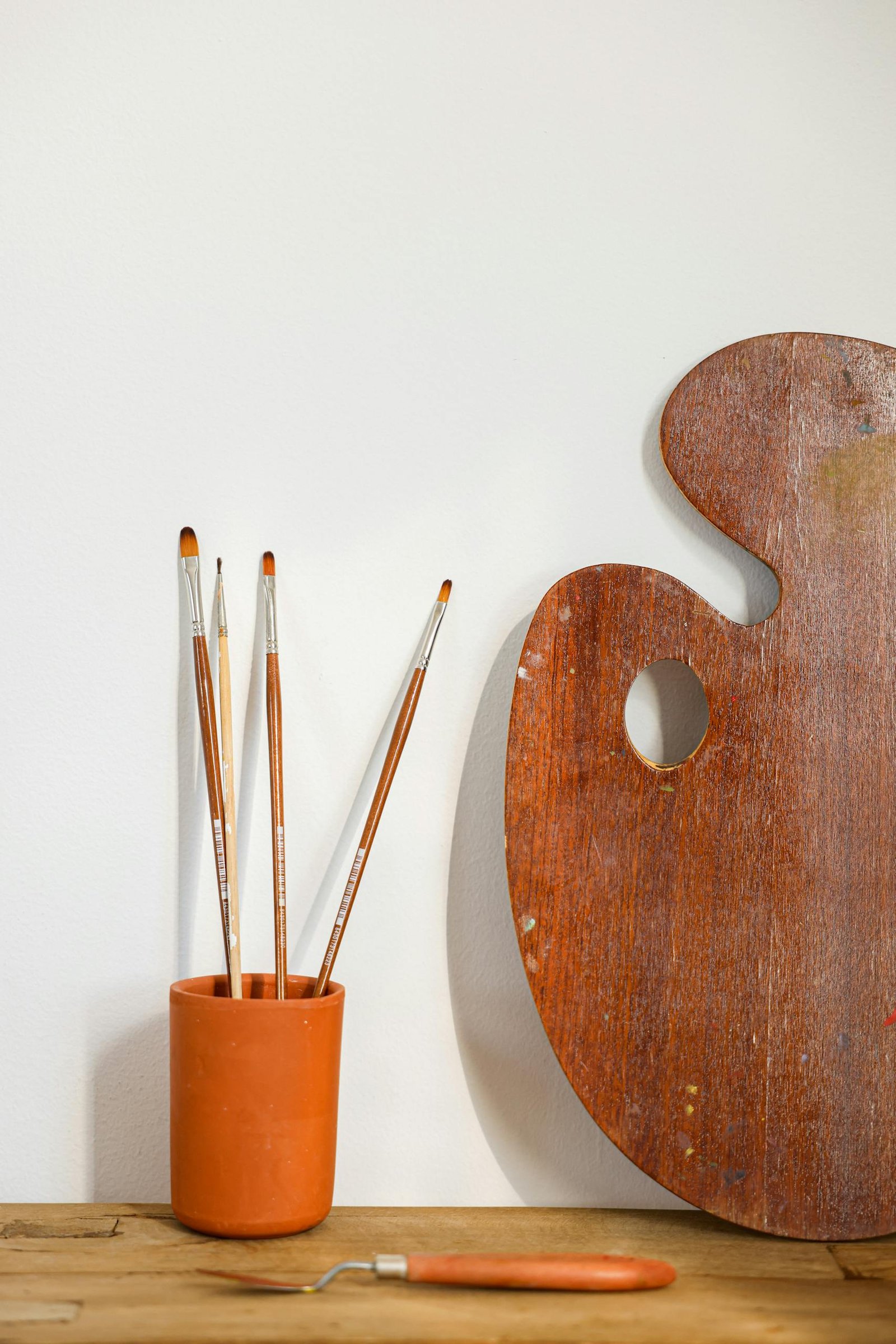 Art supplies including brushes and palette on a wooden table. Ideal for creative projects.